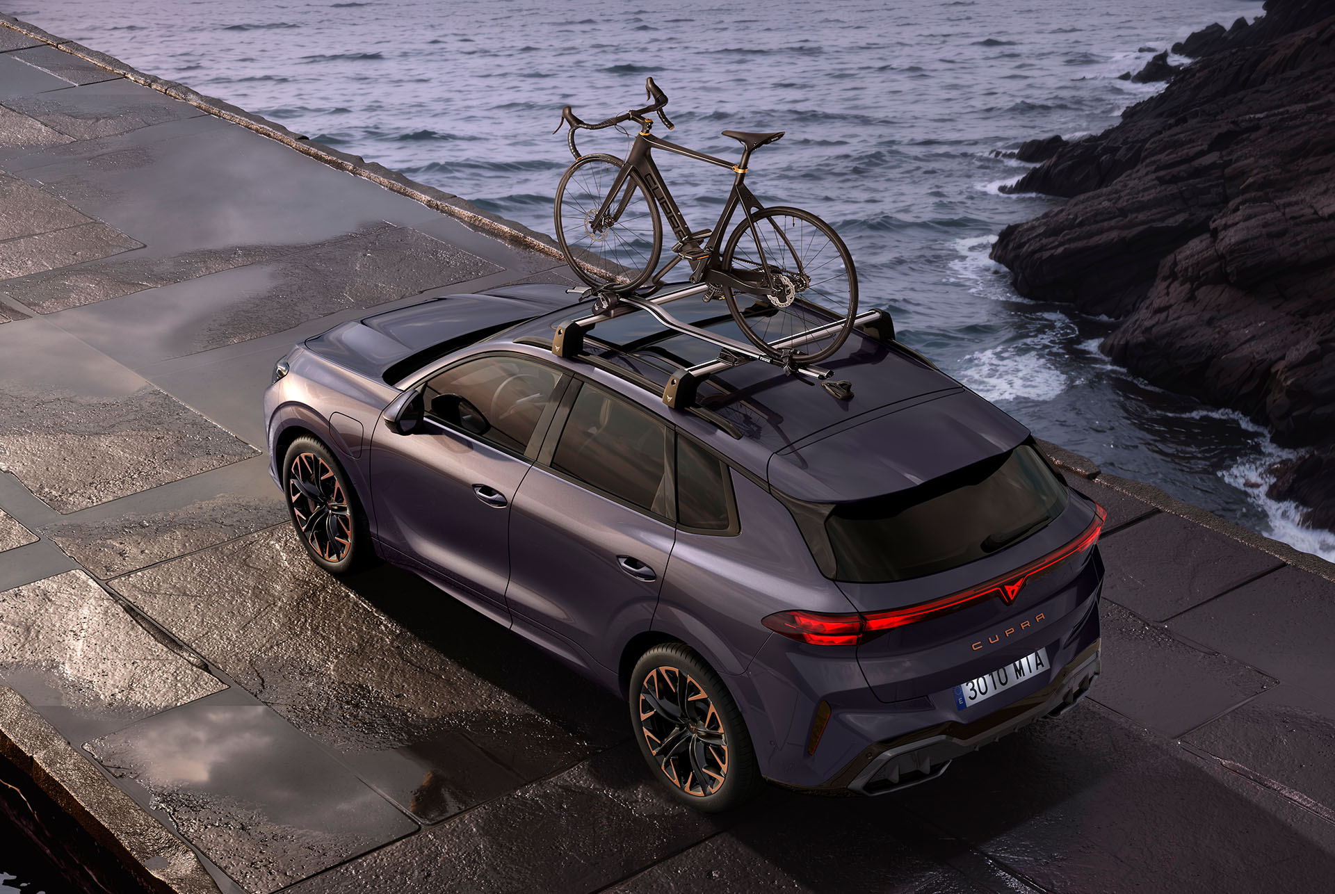 CUPRA Terramar with bike rack carrying two bikes. The SUV is parked on a coastal road, showcasing the ease of setting up the rack and its secure anti-theft system, ready for an adventure.